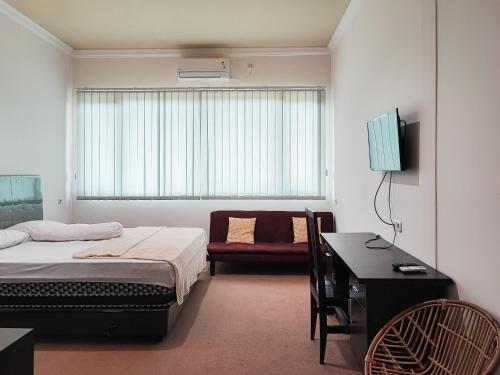 um quarto com uma cama, uma secretária e uma cadeira em RedDoorz Plus Syariah near Simpang Rimbo Jambi em Kinati
