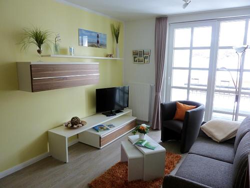 ein Wohnzimmer mit einem Sofa und einem TV in der Unterkunft Residenz am Balmer See - BS 58 mit Wellnessbereich in Balm