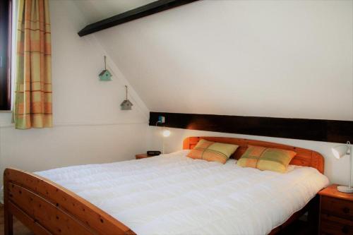 una camera da letto con un grande letto bianco con due cuscini di Achter N Diek a De Haan
