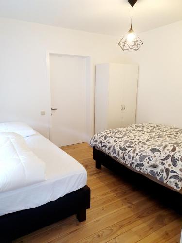 a white bedroom with a bed and a lamp at Les Bruyeres in De Haan