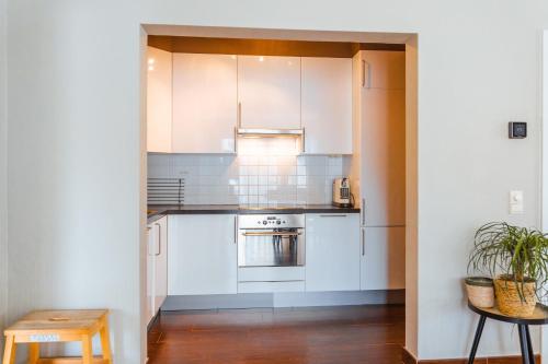 a kitchen with white cabinets and a table and a stool at Lilyta B303 in De Haan