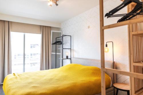 ein Schlafzimmer mit einem gelben Bett und einem Fenster in der Unterkunft Lilyta B303 in De Haan