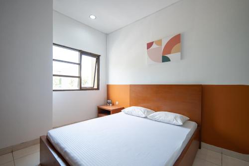 um quarto com uma cama branca e uma janela em Cove Sky City Home em Bandung