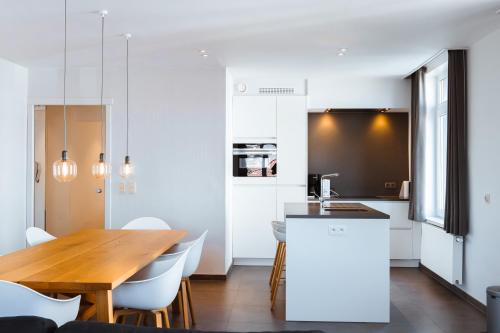 uma cozinha e sala de jantar com uma mesa de madeira e cadeiras em Beau Sejour A1 em De Haan