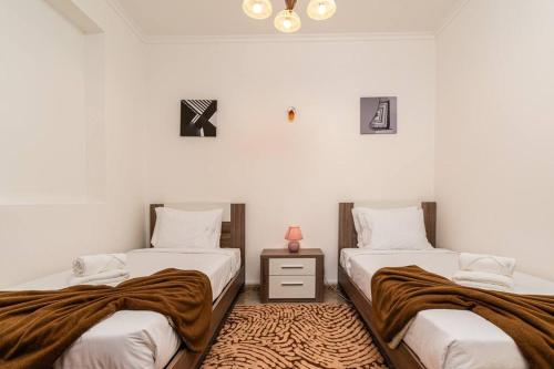 een slaapkamer met 2 bedden en een tafel met een lamp bij Noite's House I - Prazeres in Prazeres