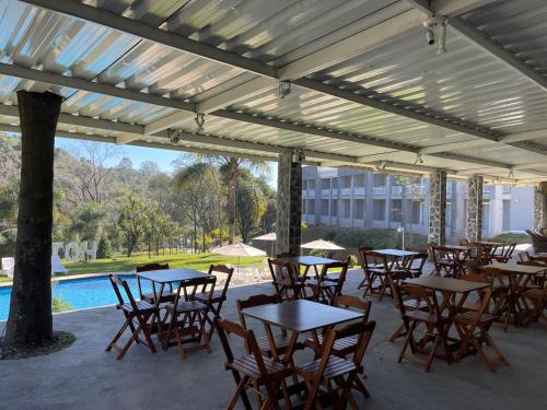 a patio with tables and chairs and a pool at DR Hotel Rio Branco do Sul in Votuverava