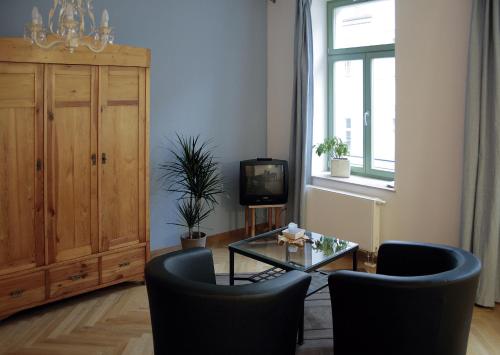 Ferienhaus im Barockviertel في درسدن: غرفة معيشة مع طاولة وكراسي وتلفزيون