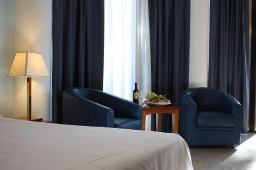 a hotel room with two chairs and a bed and a table at Hotel Terme Marine Leopoldo II TERME & SPA in Marina di Grosseto