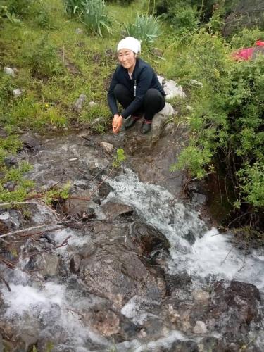 una mujer sentada en una roca junto a un arroyo en Nurbol 