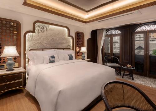 a bedroom with a large white bed and windows at CHINO@NIMMAN Luxury Boutique Hotel in Chiang Mai
