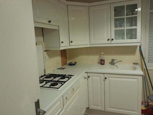 une cuisine avec des armoires blanches, un évier et une cuisinière dans l'établissement Georges Clémenceau Appartment Cannes, à Cannes