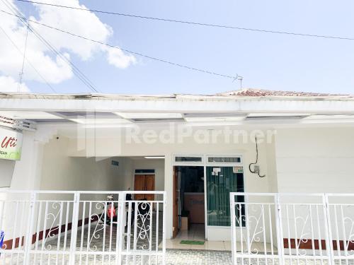 a white house with a white fence in front of it at Oma Uti Syariah Mitra RedDoorz near Stasiun Lempuyangan in Sentool