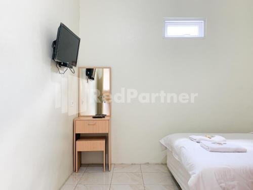 a bedroom with a bed and a tv on a wall at Oma Uti Syariah Mitra RedDoorz near Stasiun Lempuyangan in Sentool