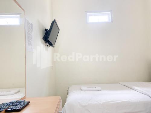 a bedroom with a bed and a desk with a monitor at Oma Uti Syariah Mitra RedDoorz near Stasiun Lempuyangan in Sentool
