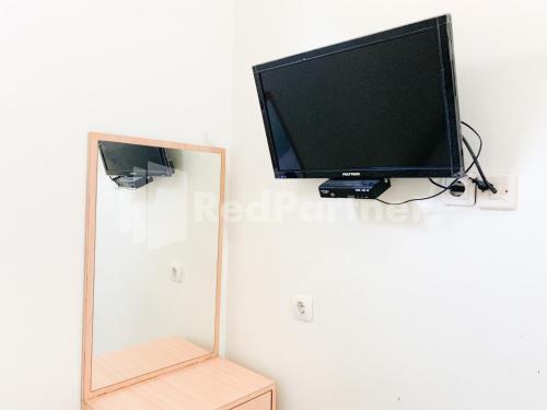 a television sitting on a wall next to a mirror at Oma Uti Syariah Mitra RedDoorz near Stasiun Lempuyangan in Sentool