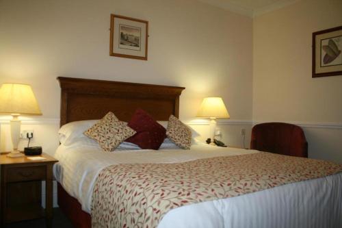 um quarto de hotel com uma cama grande com dois candeeiros em Queen's Head Inn em Nassington