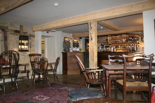 a dining room with a table and chairs and a bar at Queen's Head Inn in Nassington