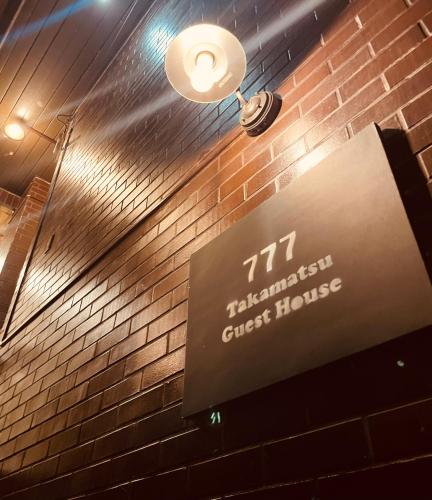 a sign on a brick wall with a clock on it at 777 Takamatsu Guest House in Takamatsu