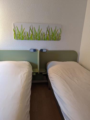 a pair of beds in a hotel room at ibis budget Saint-Omer Centre in Saint-Omer