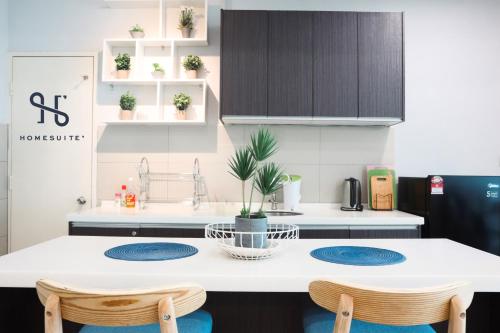 a kitchen with a white counter and blue chairs at Homesuite' Home at The Loft in Kota Kinabalu
