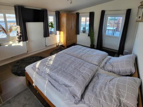 a bedroom with a large bed with pillows and windows at Ferienhaus Hanne Herrmann Hus in Esgrus