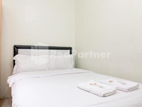 a white bed with two towels on top of it at Oma Uti Syariah Mitra RedDoorz near Stasiun Lempuyangan in Sentool