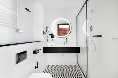Baño blanco con lavabo y espejo en Focus Hotel Premium Lublin, en Lublin
