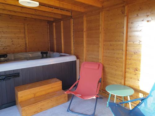 una silla roja sentada junto a una bañera en una cabaña en Les clés de la ferme - 4 chambres - proche La Loupe et Nogent-le-Rotrou - option SPA, en Sablons-sur-Huisne