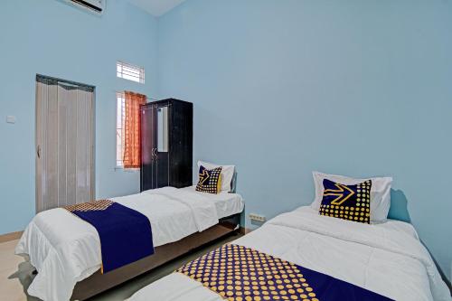 - 2 lits dans une chambre aux murs bleus dans l'établissement SPOT ON 92801 Penginapan Puti Syariah, à Pekanbaru
