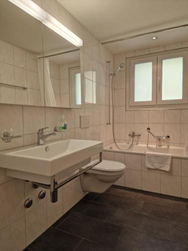 uma casa de banho com um lavatório, um WC e um espelho. em Apartment Via Surpunt - Perspektiva - 5 Rooms em St. Moritz