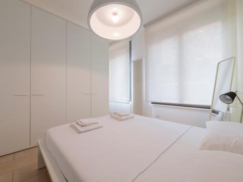 a white bedroom with a large white bed and a lamp at Youhosty - Via Savona 70 in Milan