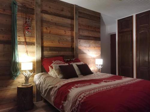1 dormitorio con 1 cama con paredes de madera y 2 lámparas en Gite Les Grillons en Belvédère