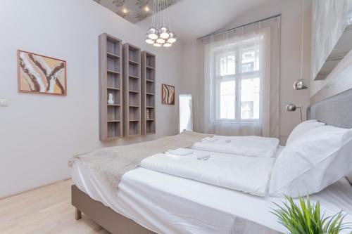 a white bedroom with a large bed and a window at Andrássy Str. Luxury Apartment in Budapest