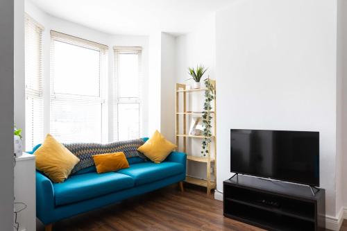 a living room with a blue couch and a flat screen tv at Belfast City - 3 Bed Cosy Terrace Home - Hip and Trendy Ormeau Road in Belfast