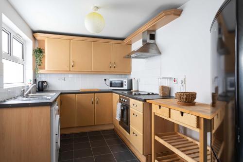 a kitchen with wooden cabinets and a counter top at Belfast City - 3 Bed Cosy Terrace Home - Hip and Trendy Ormeau Road in Belfast