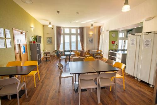 a dining room with tables and chairs and a kitchen at Oban Youth Hostel in Oban