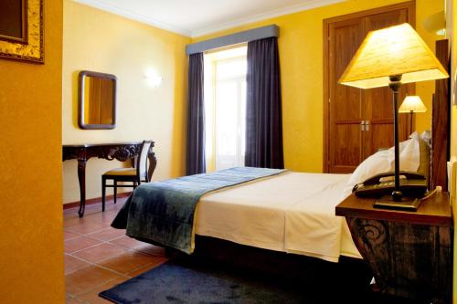 a bedroom with a bed and a table with a lamp at Hotel Convento D'Alter by Asite Hotels in Alter do Chão
