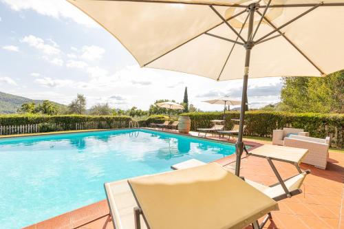 a swimming pool with an umbrella and two chairs and a table and an umbrella at Borgo Dolci Colline Resort Cipresso in Castiglion Fiorentino