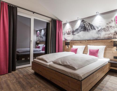 a bedroom with a large bed with pink pillows at first mountain Hotel Zillertal in Aschau