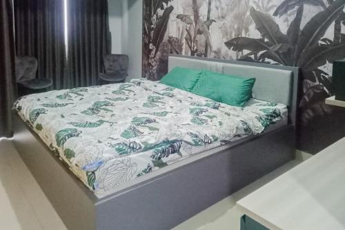 a bed with a green and white comforter on it at RedLiving Apartemen Royal Sentul Park - Budi Property in Cikeas
