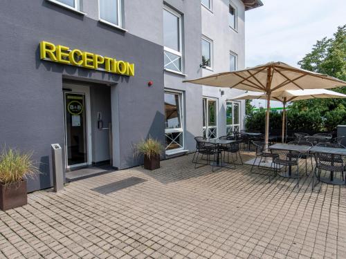 un restaurante con mesas, sillas y sombrilla en B&B Hotel Schweinfurt-Süd, en Schweinfurt