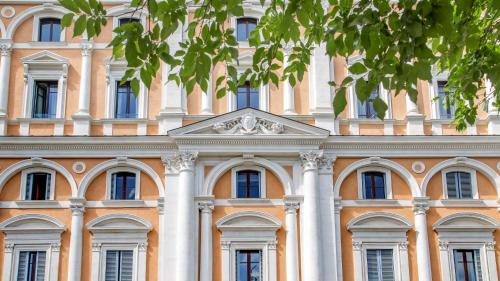 an orange building with white columns and windows at Princeps Boutique Hotel in Rome