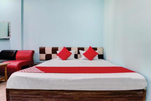 a bedroom with a bed with red pillows and a red chair at Supriya Palace in Lucknow