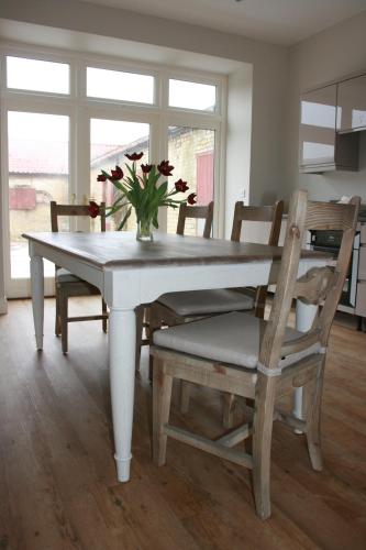 uma mesa de jantar e cadeiras com um vaso de flores em Owl Barn em King's Lynn