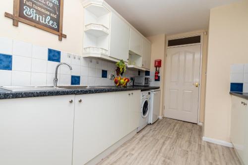 une cuisine avec des armoires blanches et un évier dans l'établissement Fife - Driveway Parking Spacious 4 bed house Sleeps 6 Ideal Contractor Accommodation, à Gateshead