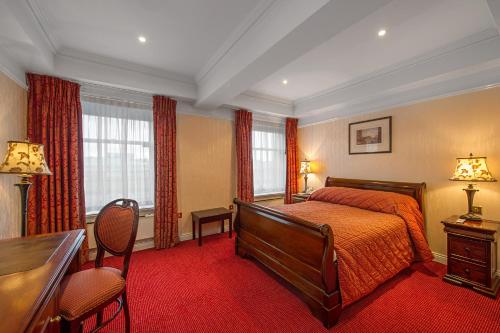 Wynn's Hotel في دبلن: غرفة نوم بسرير ومكتب ونوافذ