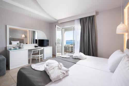 Habitación de hotel con cama blanca grande y escritorio. en Alexandros Palace en Ouranoupoli