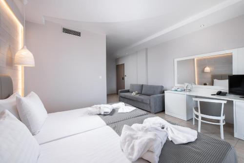 a white bedroom with a white bed and a kitchen at Alexandros Palace in Ouranoupoli