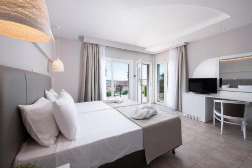 a bedroom with a bed and a desk and a television at Alexandros Palace in Ouranoupoli