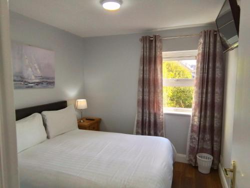 a bedroom with a white bed and a window at Wild Atlantic Accommodation 70 Burnside in Letterkenny